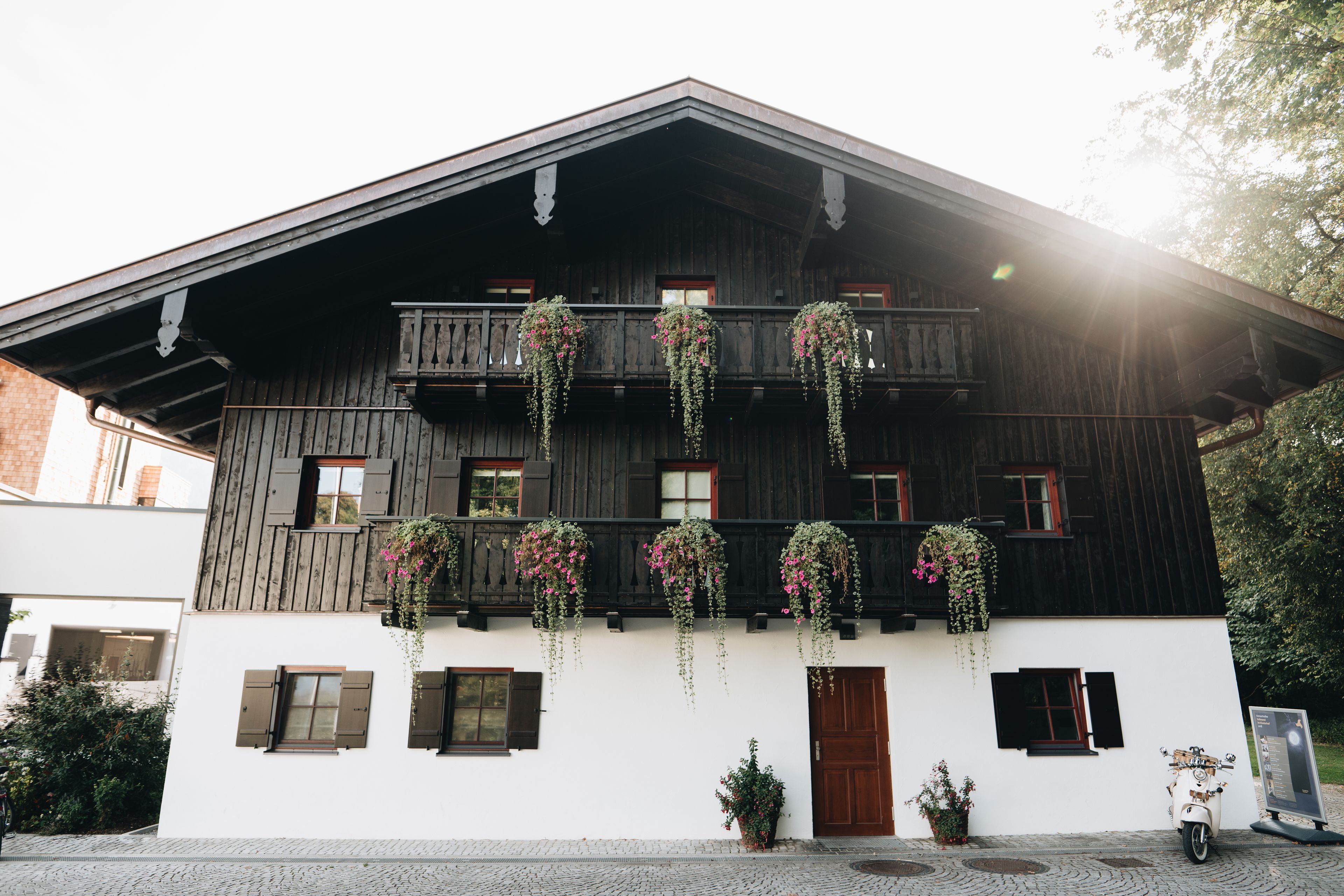 A traditional wooden building with a balcony, potted plants, and a scooter.