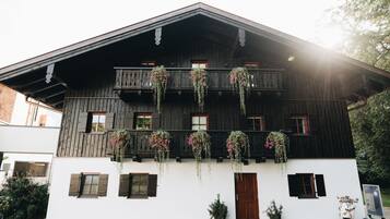 A traditional wooden building with a balcony, potted plants, and a scooter.
