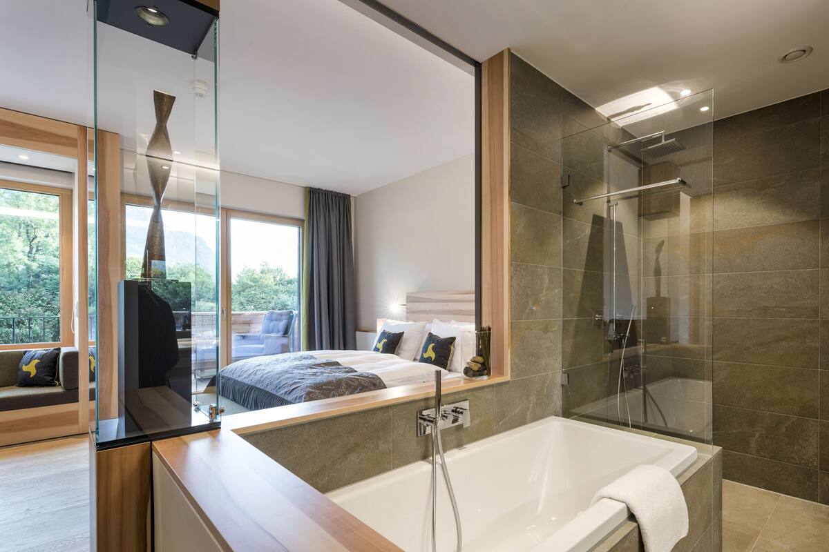 A modern bathroom with a glass-enclosed shower, a white bathtub, and a large mirror reflecting the room.