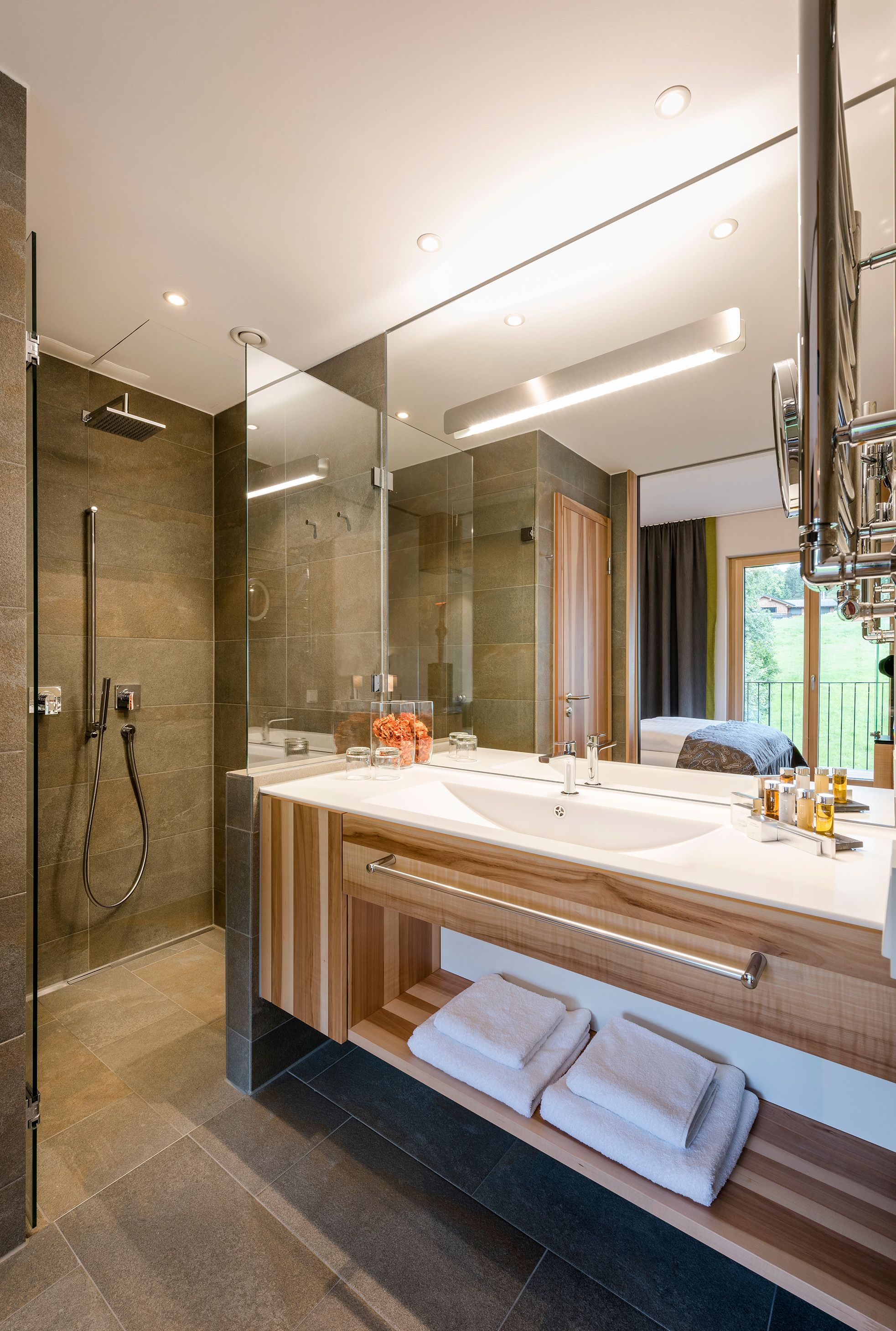 Un baño moderno con un espejo grande, lavamanos dobles y cabina de ducha.