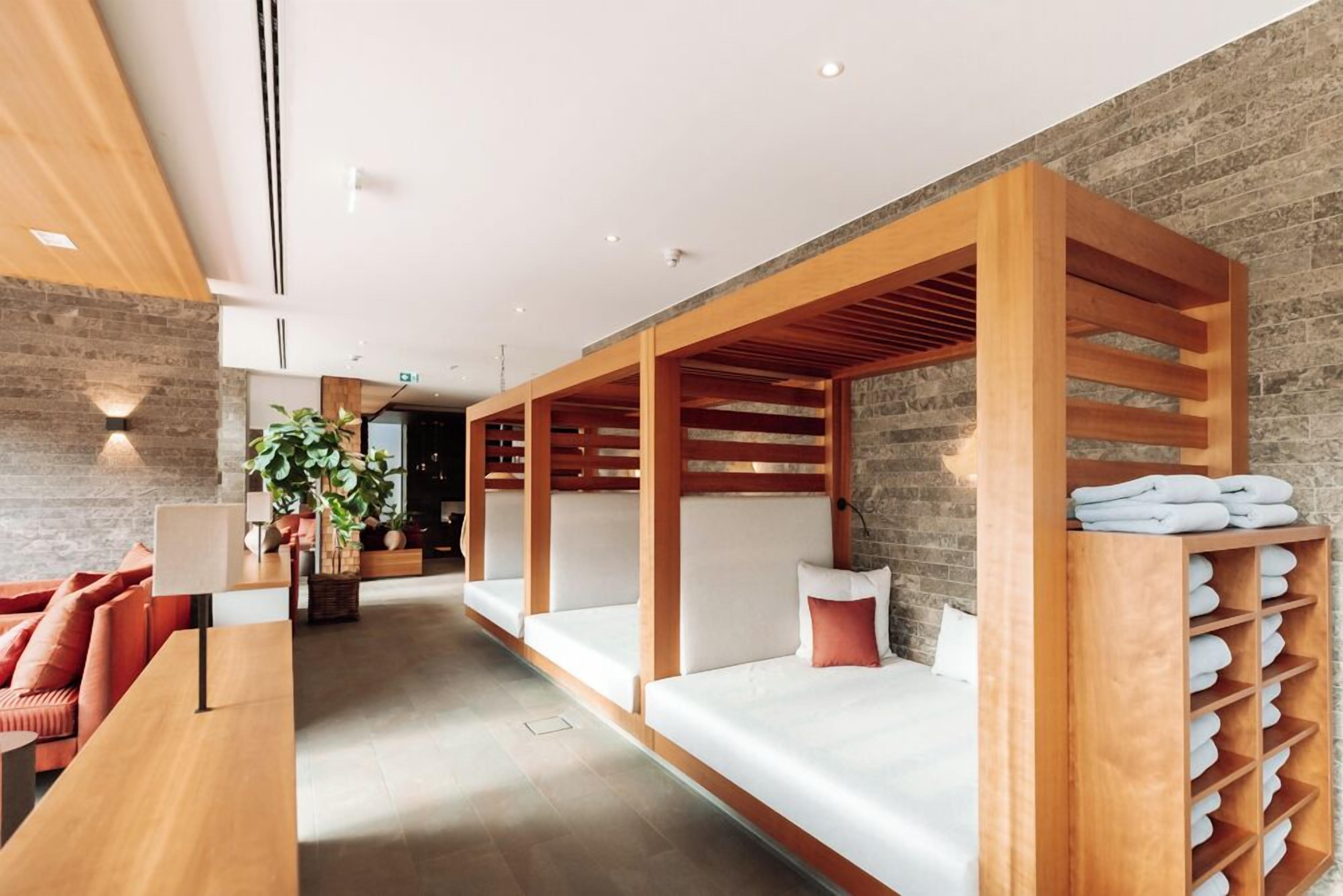 Una hall d'albergo moderna con scrivania in legno, zona relax e porta asciugamani a parete.