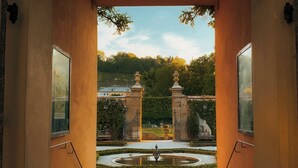 An arched entrance with a view of a garden and a fountain. - Klosterhof - Alpine Hideaway & Spa (Bayerisch Gmain)