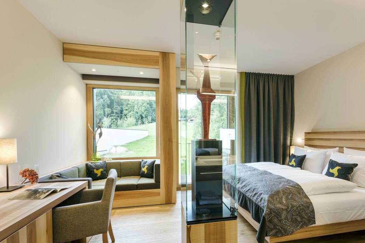 A modern hotel room with a bed, a desk, and a seating area.