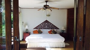 Quarto com uma cama grande, ventoinha no teto e cabeceira de madeira.