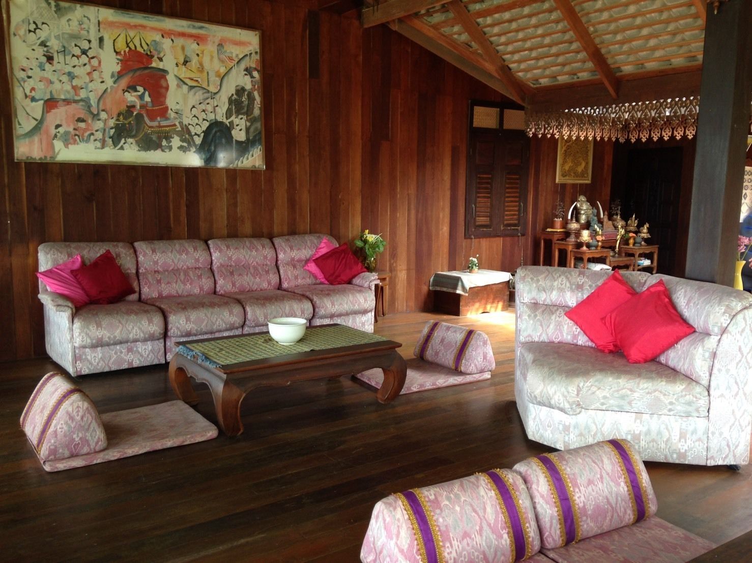 Ein traditionelles Holzinterieur mit zwei gemusterten Sofas, einem Holztisch und einem dekorativen Gemälde an der Wand.