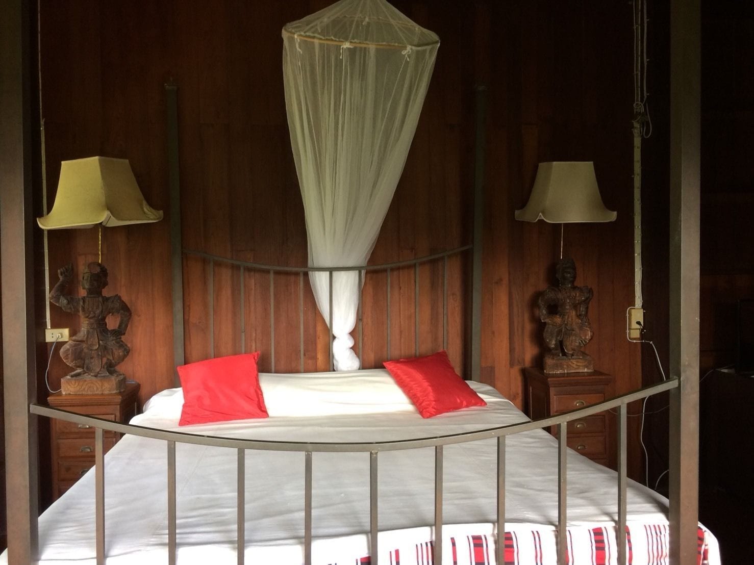 A bed with a canopy, two nightstands with lamps, and a wooden wall.