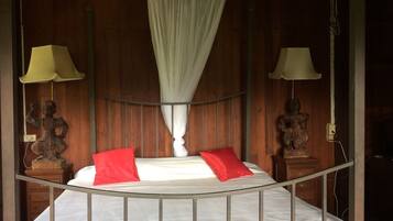 A bed with a canopy, two nightstands with lamps, and a wooden wall.