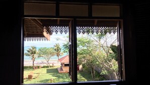Janela com vista para a praia e um jardim.