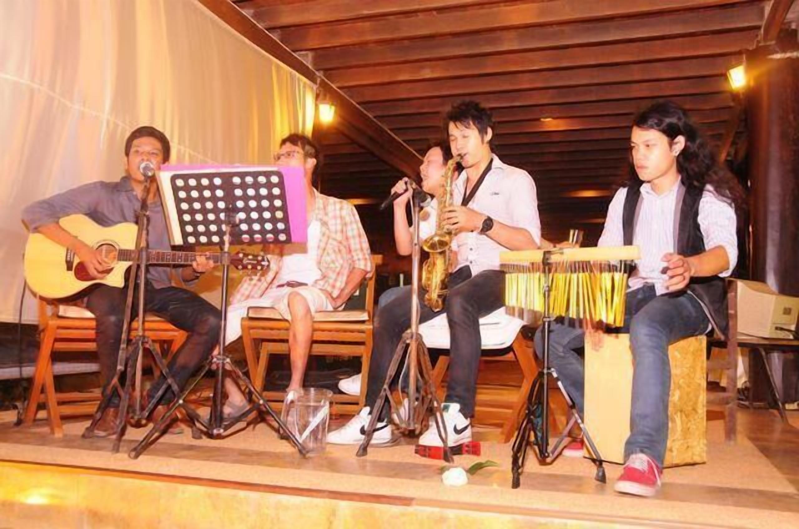 A group of musicians performing on a stage with musical instruments and a music stand.
