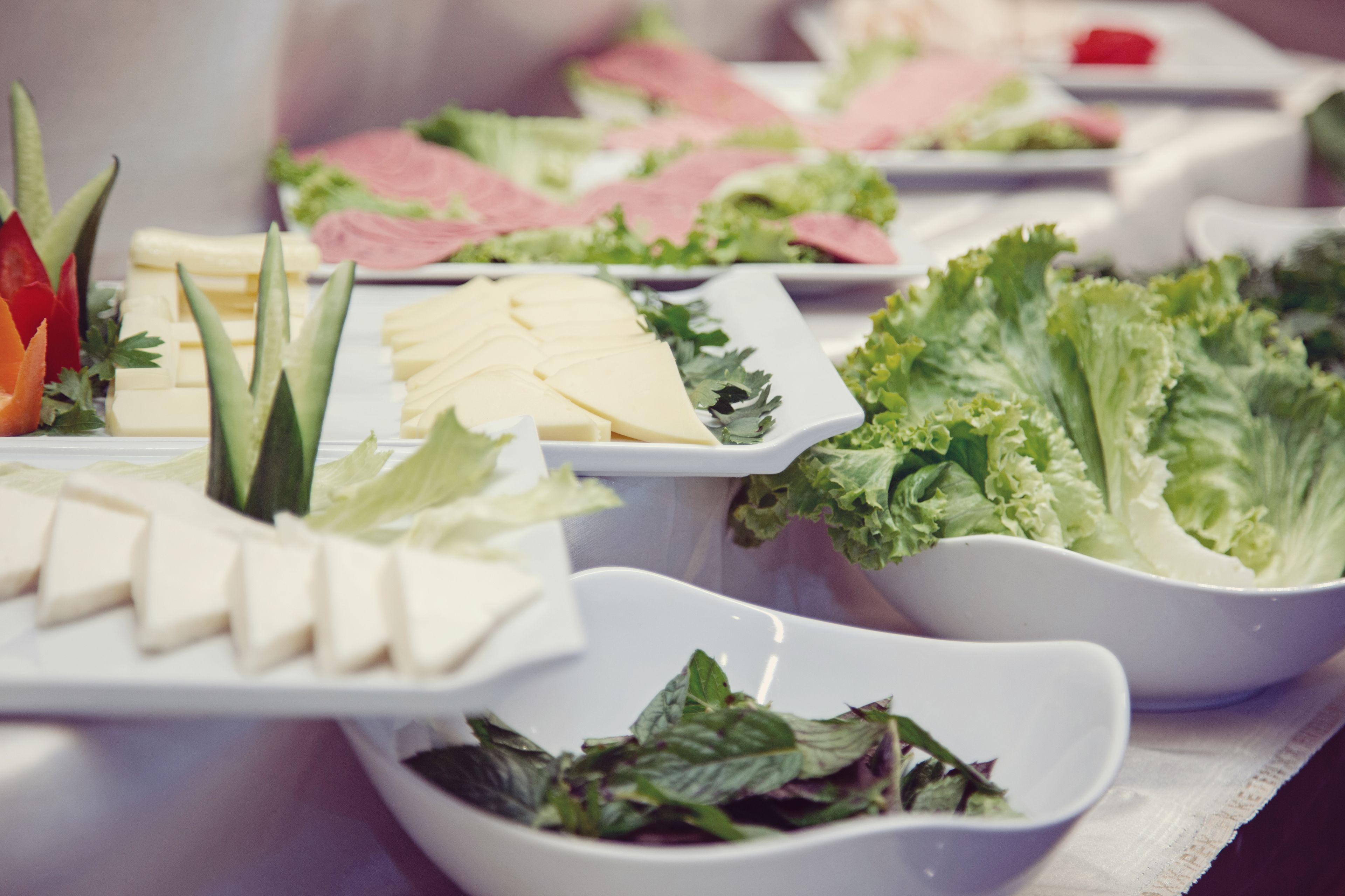 A buffet table with various food items including cheese, vegetables, and meats.