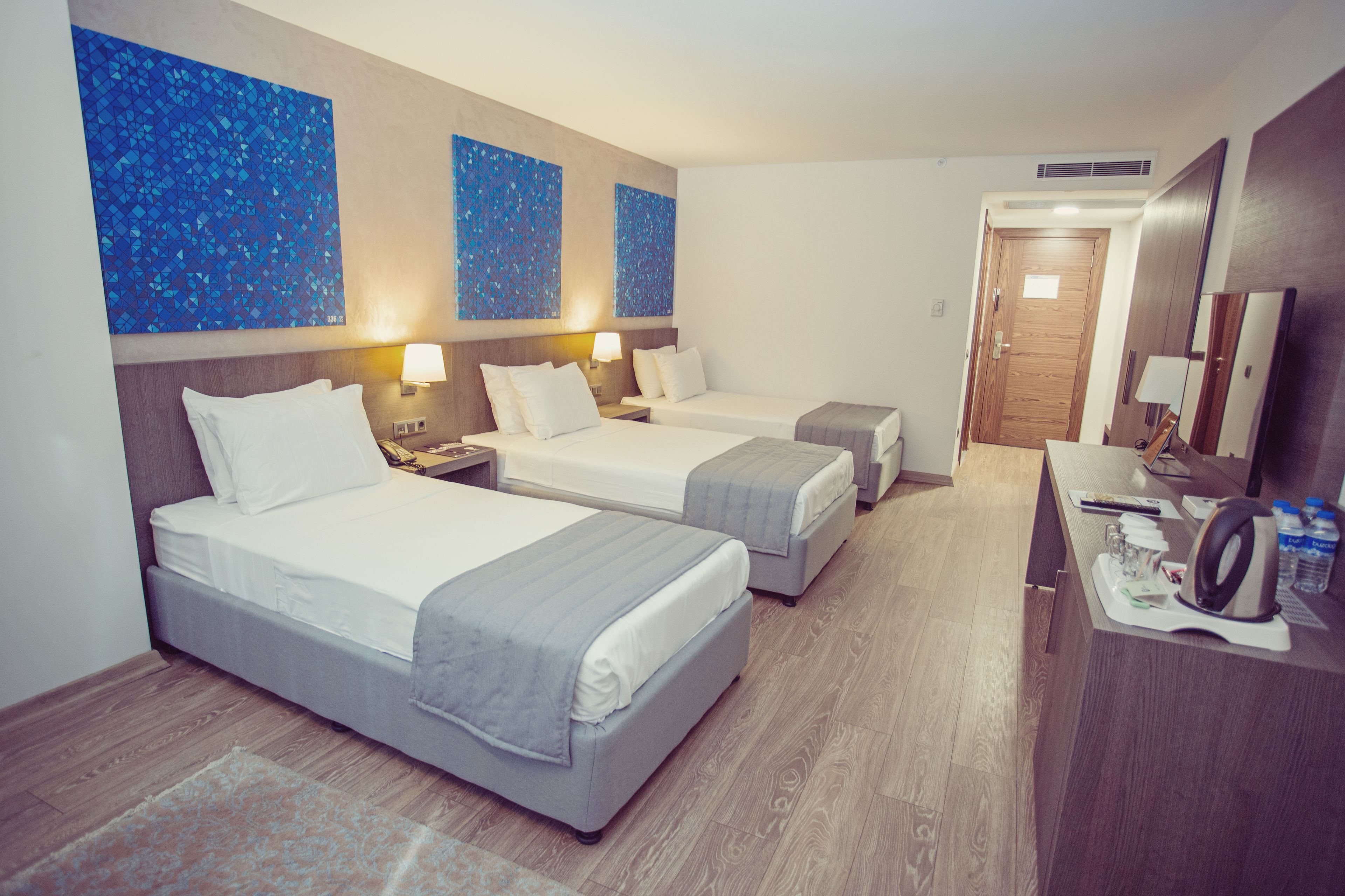 A hotel room with two beds, a desk, and a mirror.