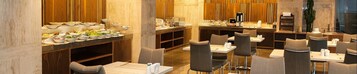 A modern dining area with multiple tables and chairs, a buffet with various dishes, and a bar area with a counter and seating.