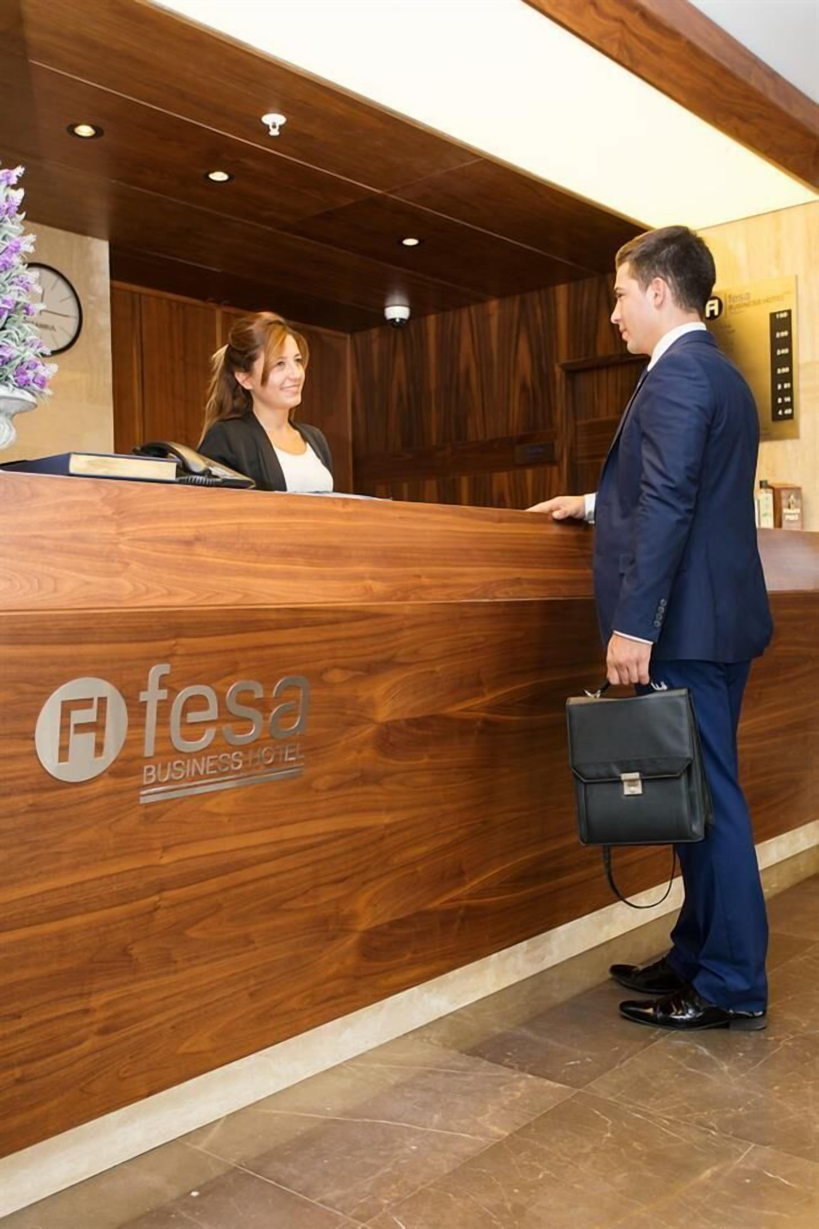 A reception desk at a business hotel with a wooden finish and a logo.
