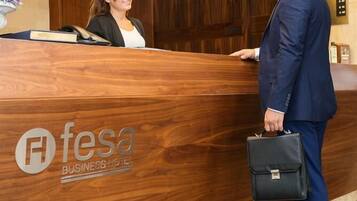 A reception desk at a business hotel with a wooden finish and a logo.