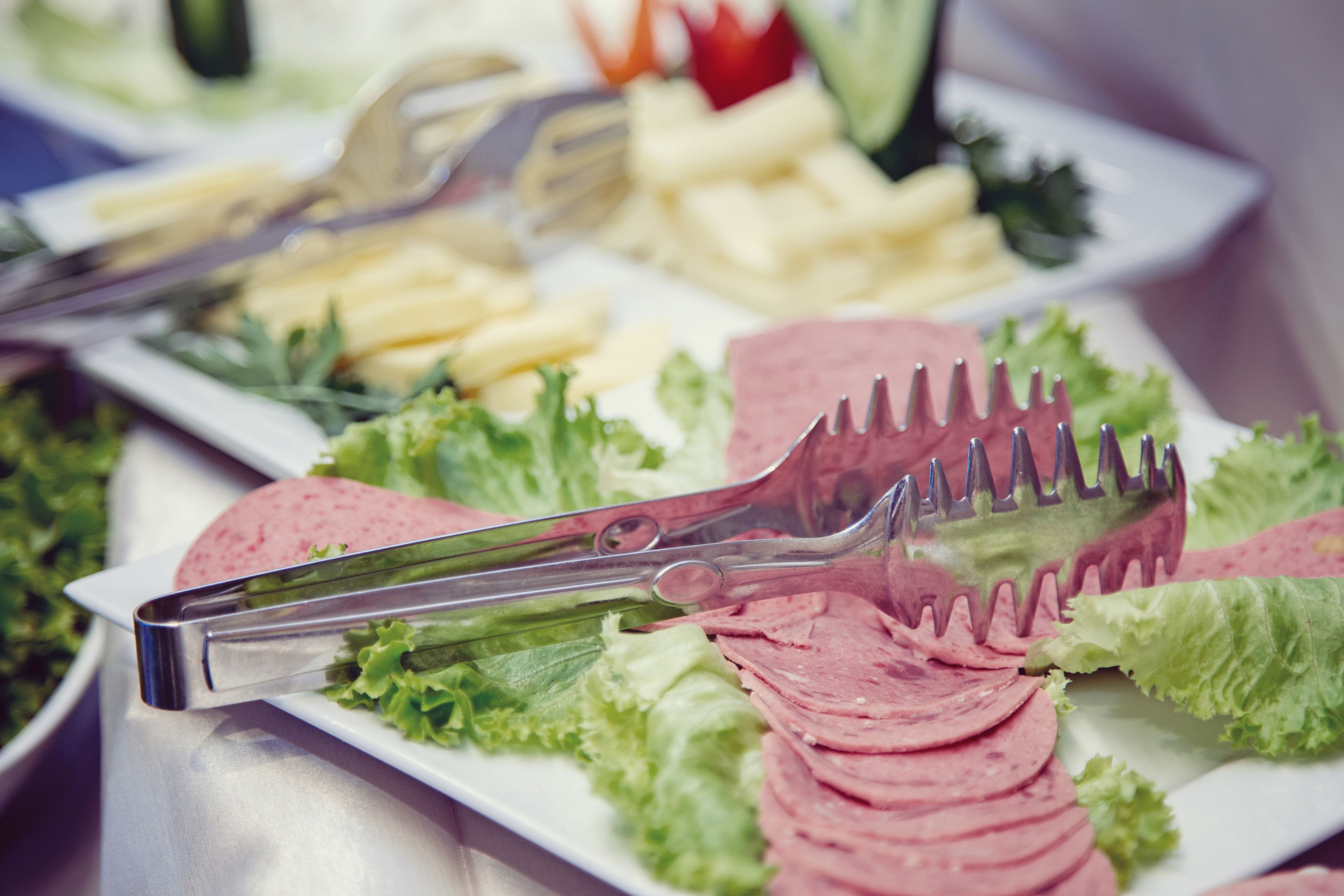 A buffet table with various food items including sliced meats, cheeses, and vegetables.