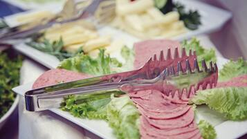 A buffet table with various food items including sliced meats, cheeses, and vegetables.