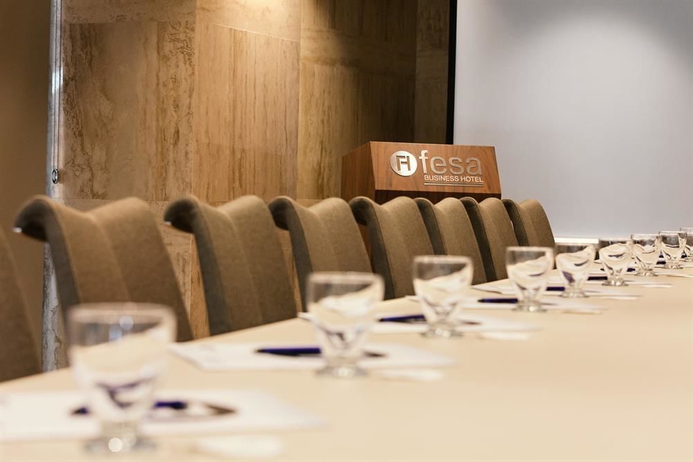 Une salle de conférence équipée d’une longue table, de chaises et d’un panneau indiquant qu’il s’agit d’un hôtel d’affaires.