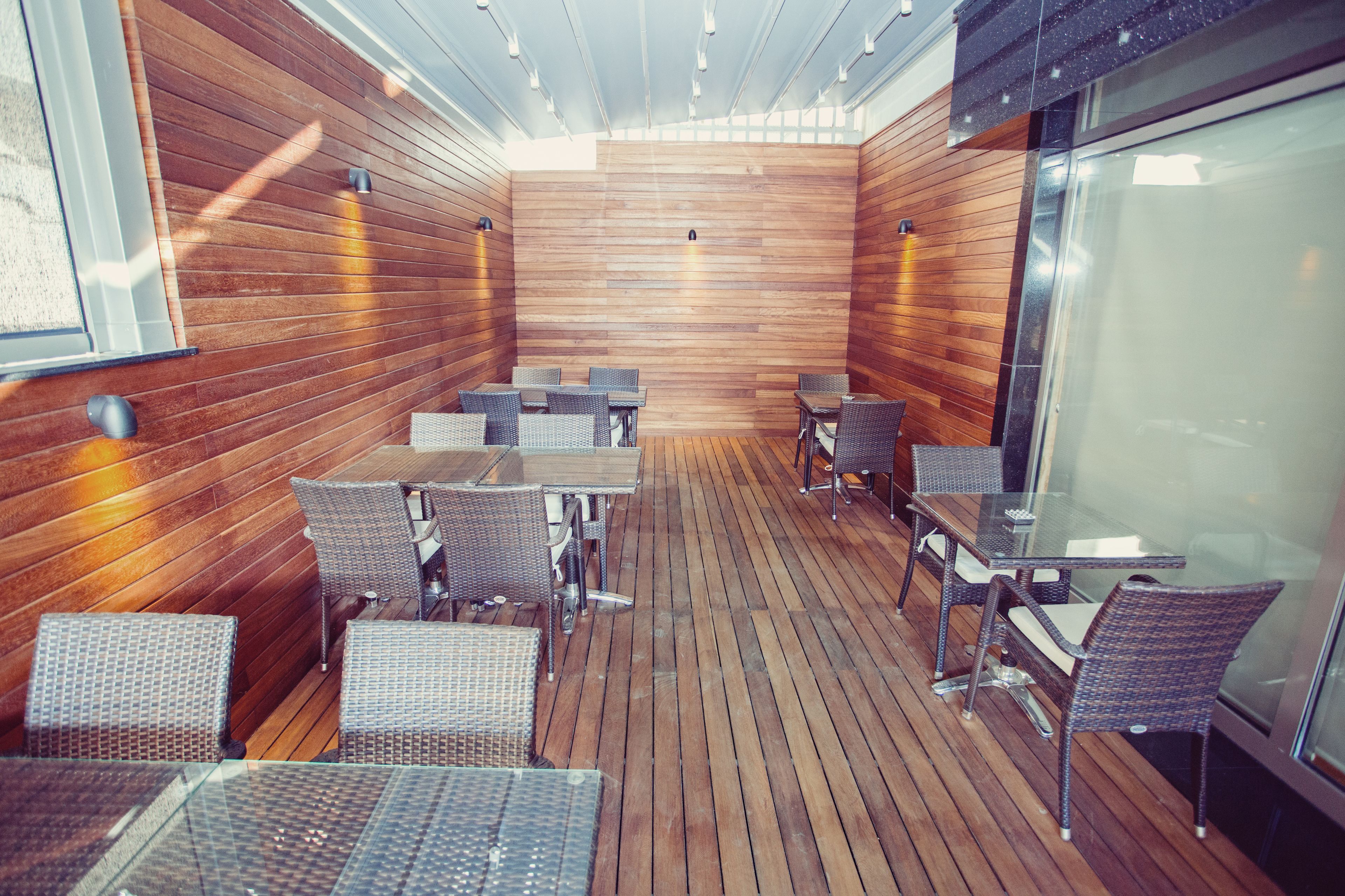 A wooden-paneled room with tables and chairs, large windows, and a glass partition.