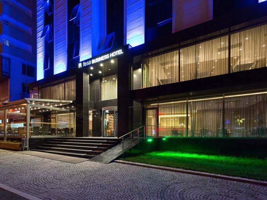 Un hotel para negocios con fachada de vidrio, entrada cubierta e iluminación exterior.