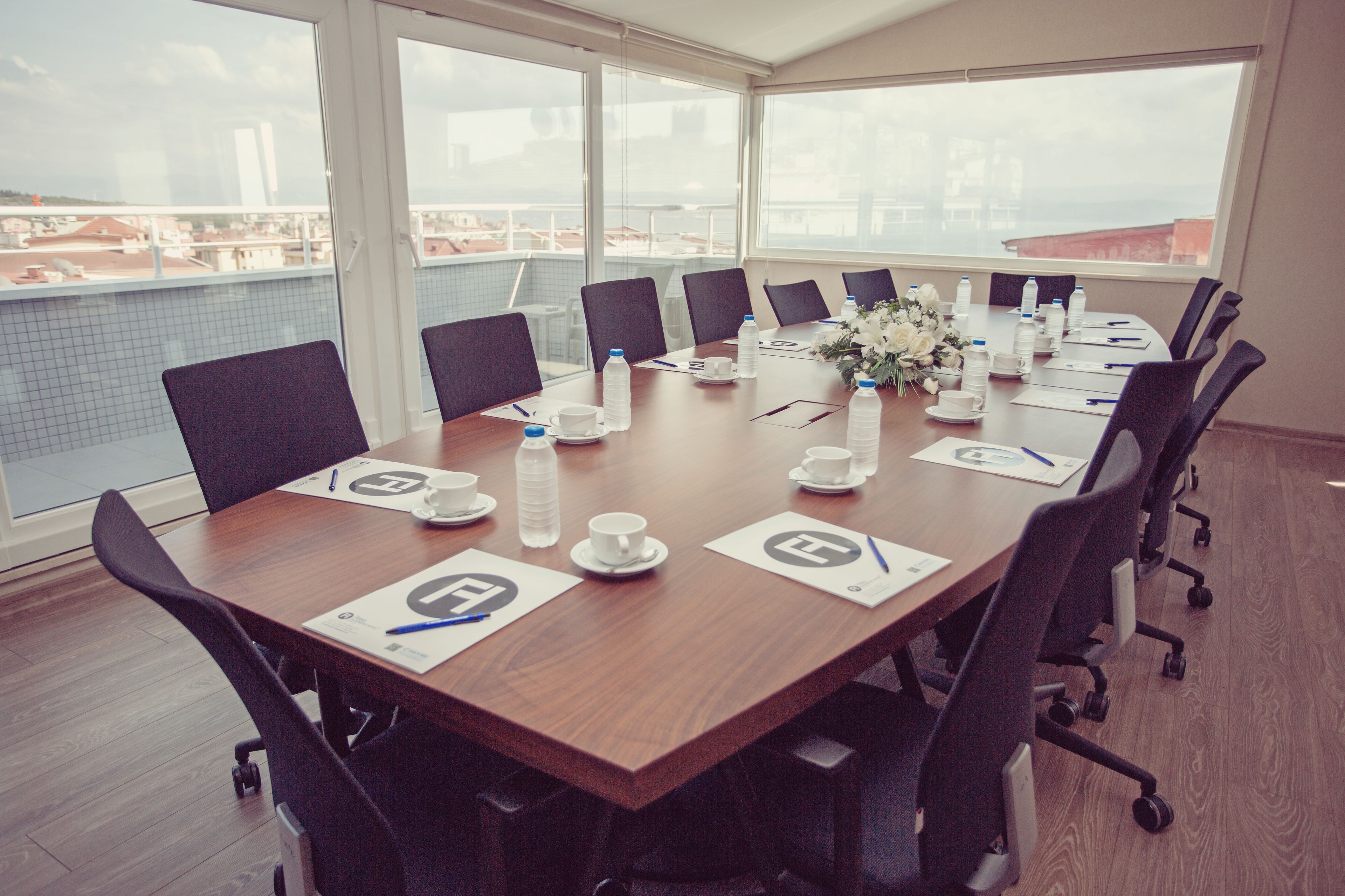 A conference room with a long table, chairs, water bottles, and a flower arrangement.