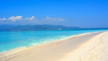 Di pantai, kursi berjemur, payung pantai, dan handuk pantai