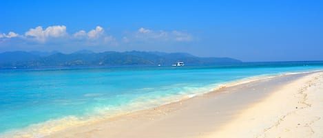 Di pantai, kursi berjemur, payung pantai, dan handuk pantai