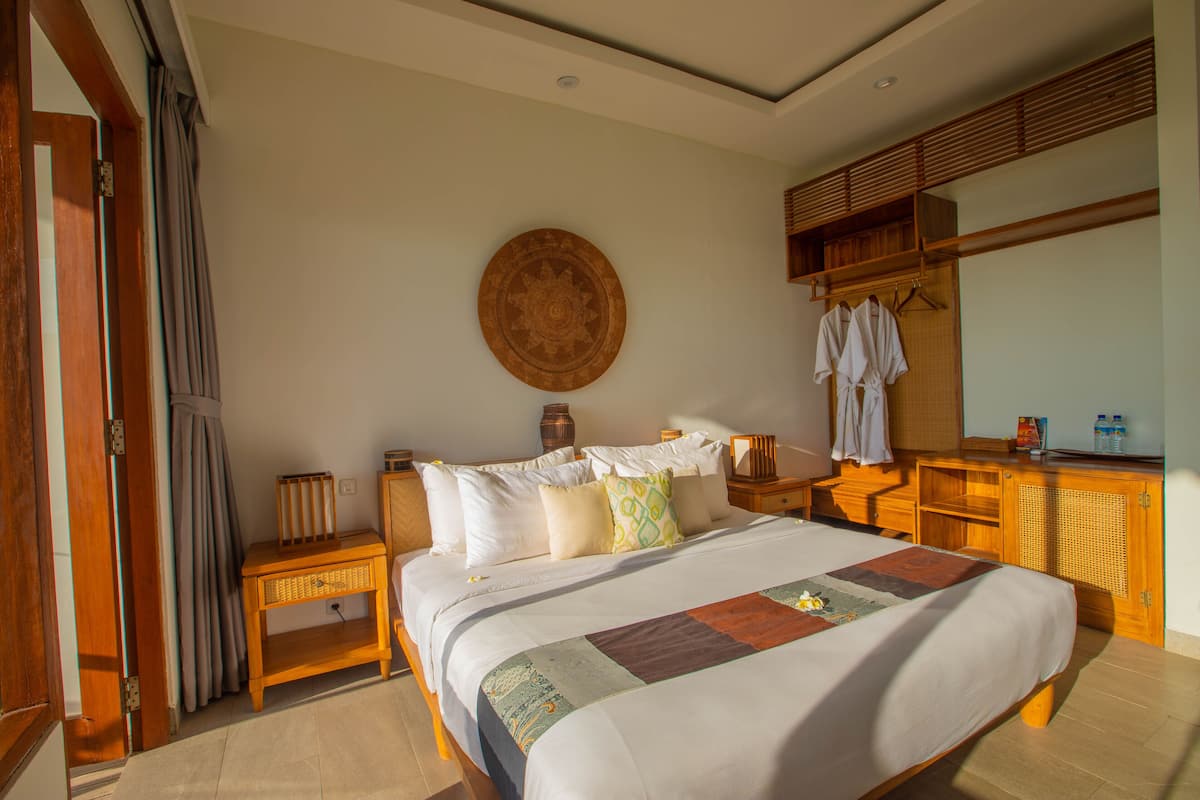 A well-lit bedroom with a large bed, wooden furniture, and a mirror.