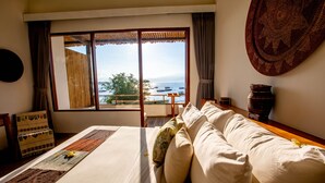 Een hotelkamer met een groot bed, uitzicht op zee en een houten vloer.