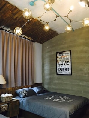 A bedroom with a wooden ceiling, a bed with a blue blanket, and a wall-mounted light fixture. - Jing Shan (Tainan)