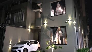 A modern two-story building with a white car parked in the driveway.