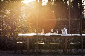Un ensemble de table et de chaises pour les repas en plein air, entouré de verdure et délimité par une clôture en métal.