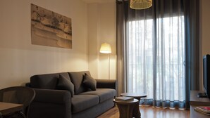 Un salon moderne avec un canapé, une petite table, une lampe et un téléviseur.