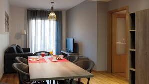 Un salon moderne avec une table à manger, un canapé et un téléviseur.