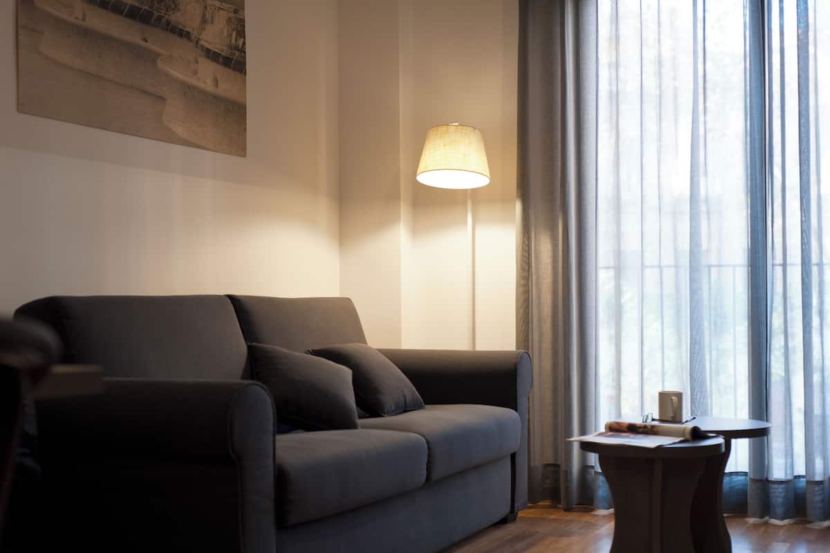 A modern living room with a dark grey sofa, a floor lamp, and a small table.