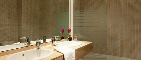 A bathroom with two sinks, a mirror, and a shower.