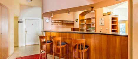 A kitchen with wooden bar stools, a red rug, and a clock on the wall.