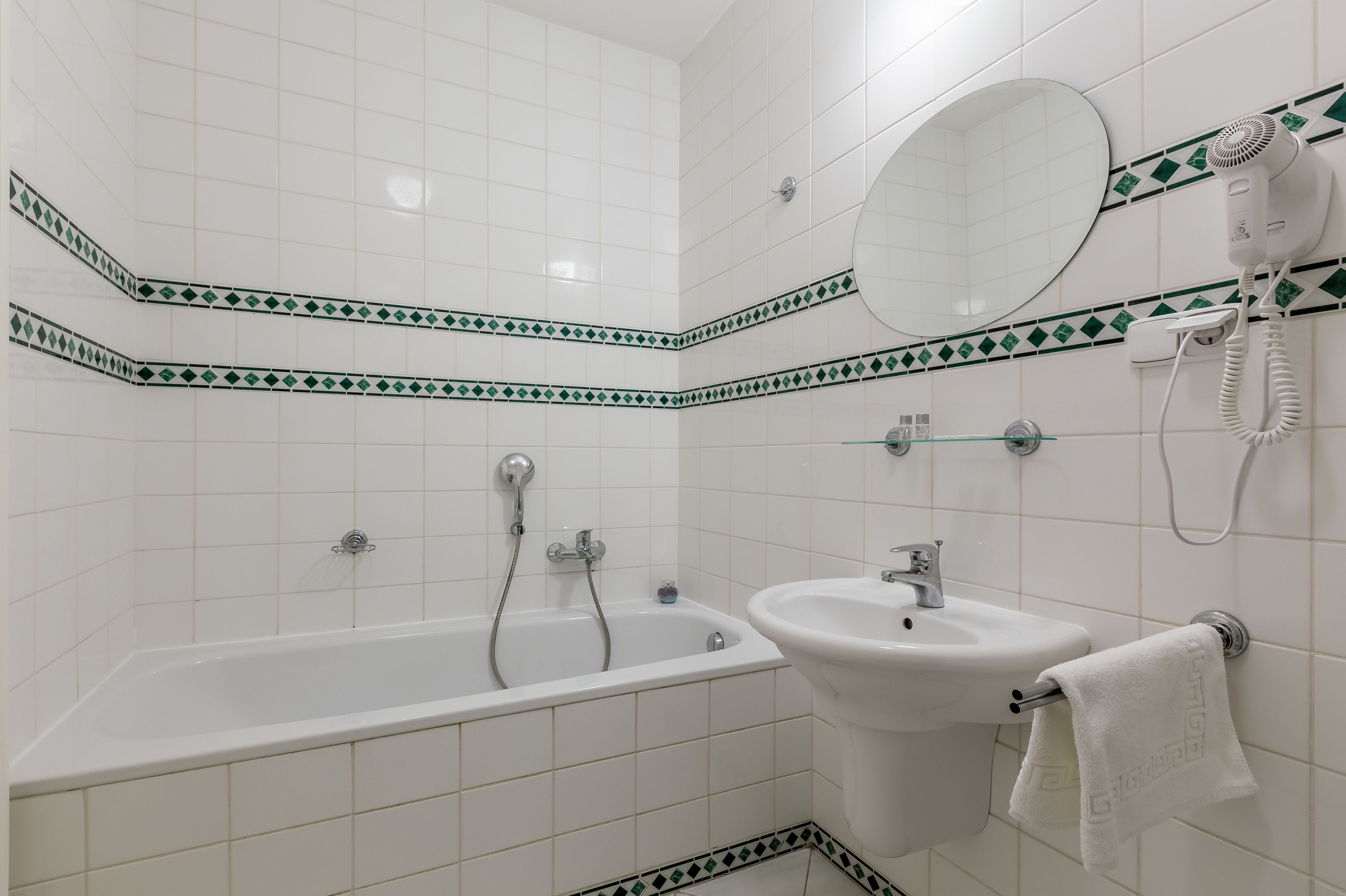Een badkamer met een bad, een wastafel, een spiegel en een haardroger.