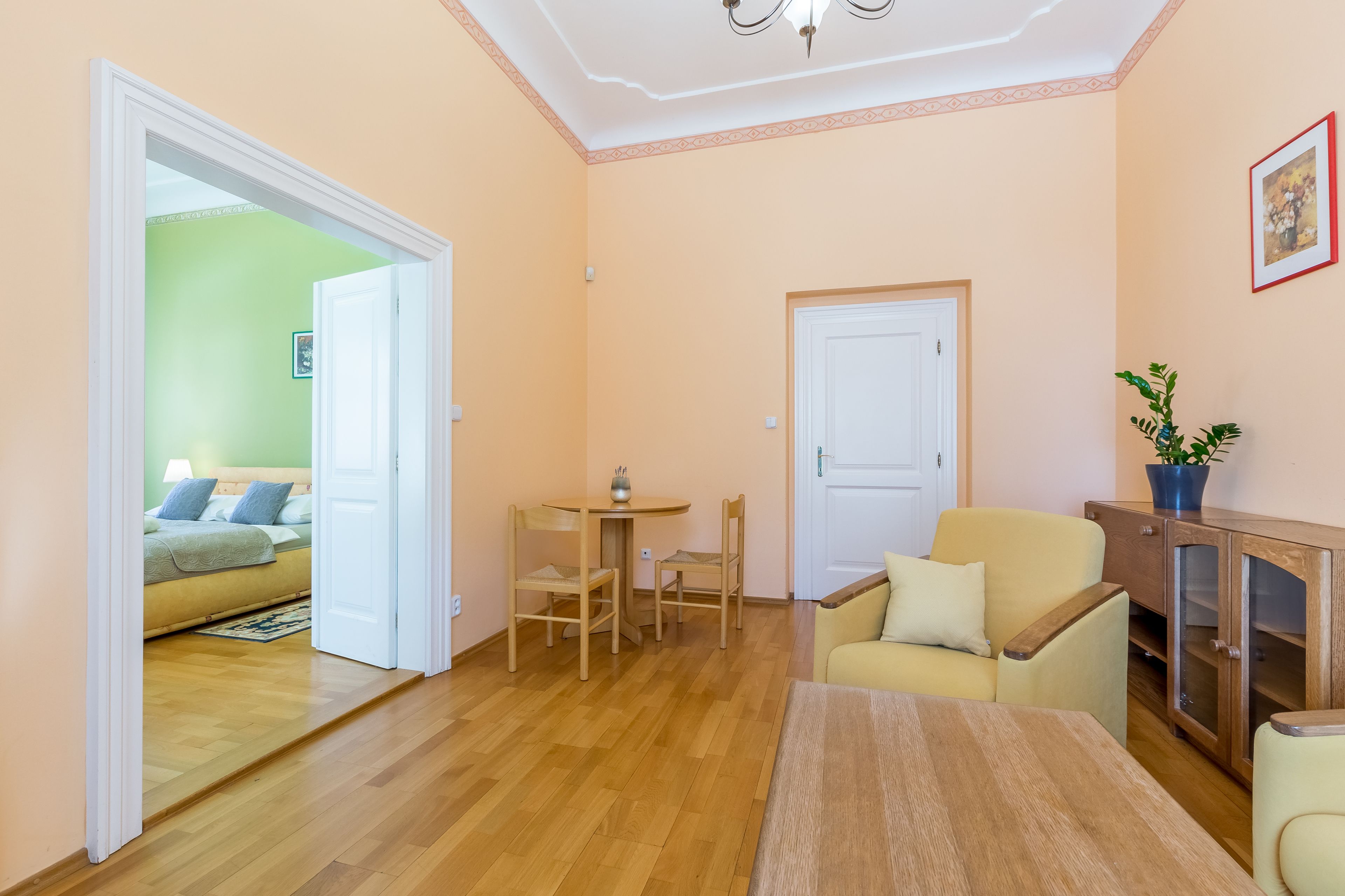 Een woonkamer met een houten vloer, een ronde tafel met stoelen, een bank en een kast.