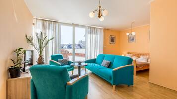 A modern living room with teal sofas, a wooden coffee table, and a large window with curtains.