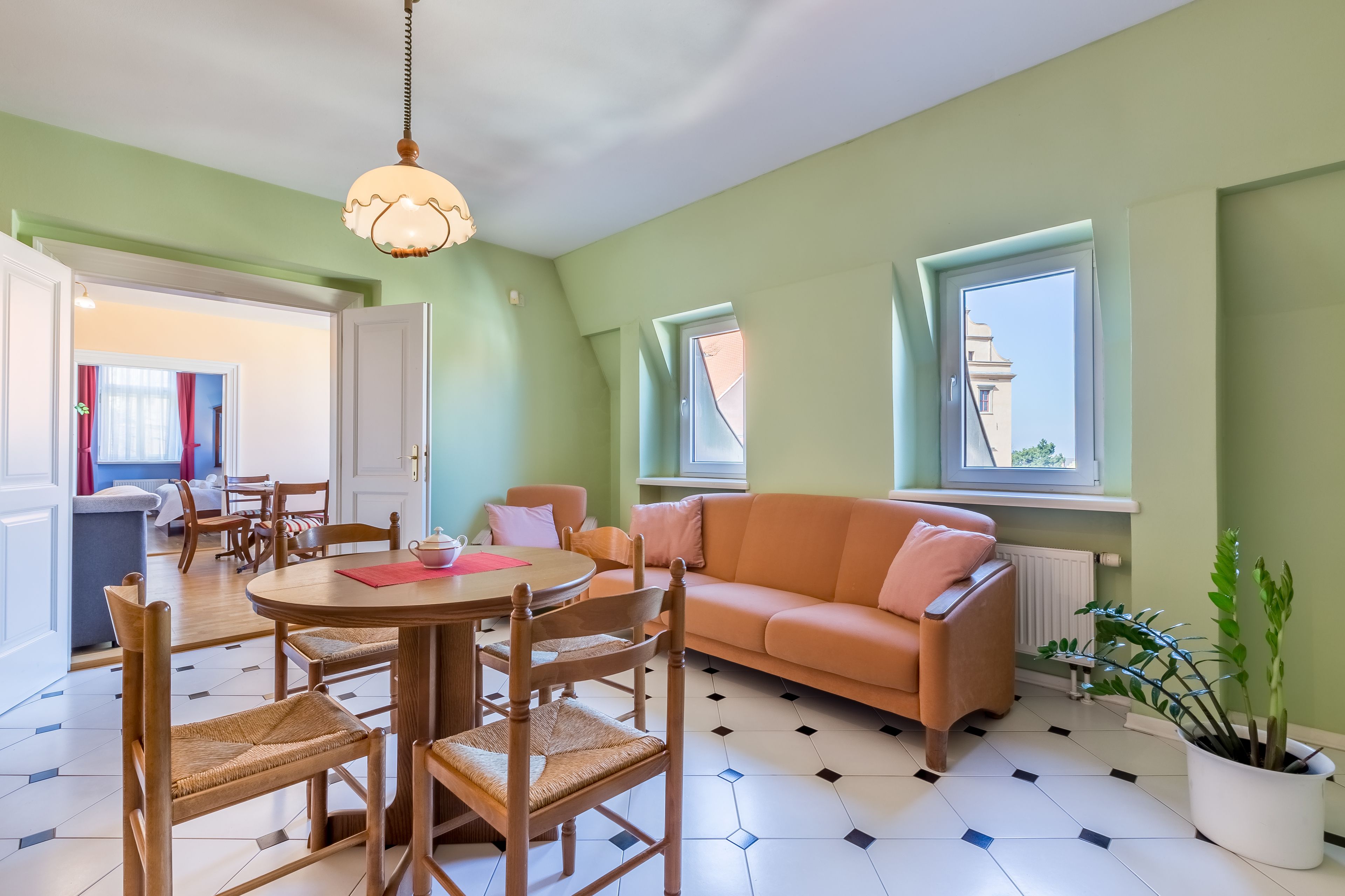 Ein gemütliches Wohnzimmer mit einem runden Tisch, Holzstühlen, einer Couch und einem Blumentopf.