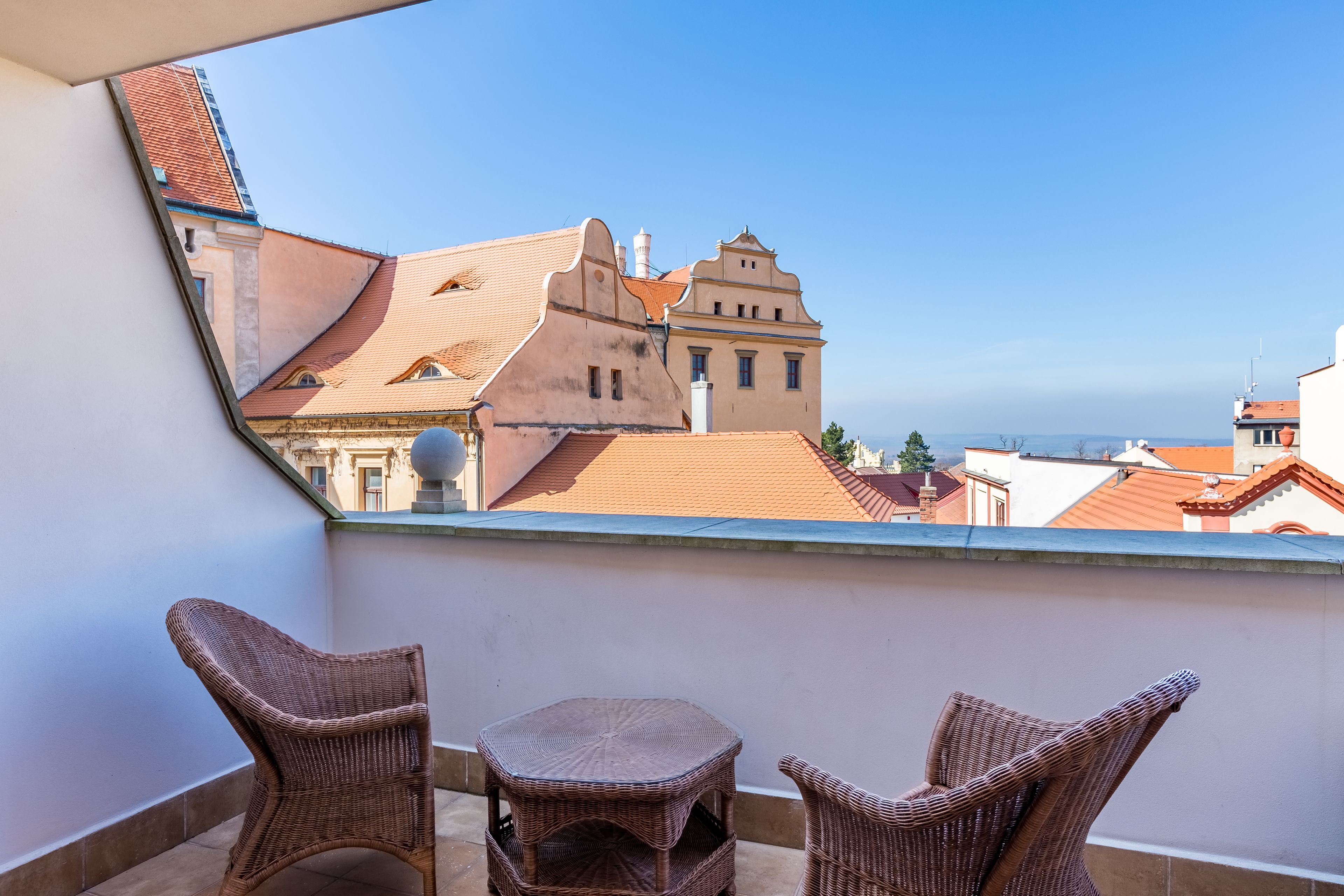 A balcony with wicker furniture and a view of buildings.