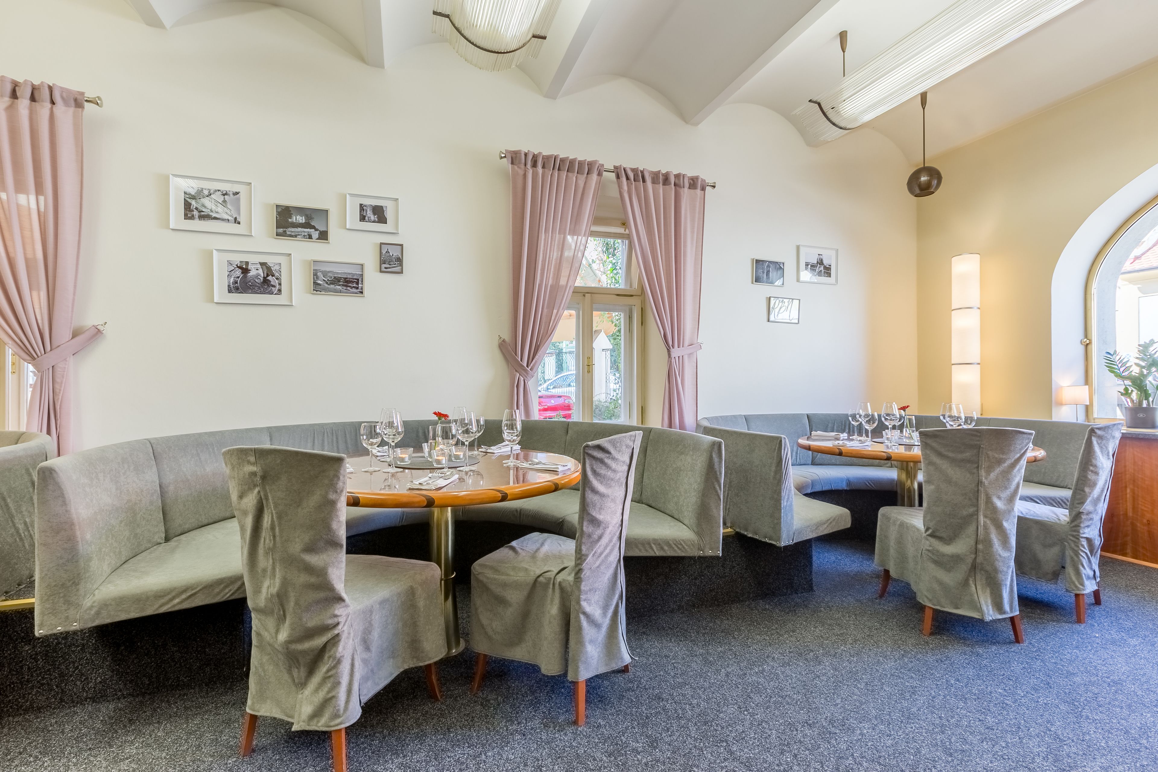 A dining area with a round table, cushioned chairs, and framed pictures on the wall.
