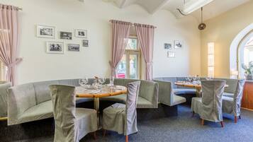 A dining area with a round table, cushioned chairs, and framed pictures on the wall.