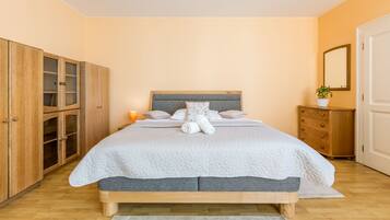 A bedroom with a bed, wooden wardrobe, bedside table, and a mirror.