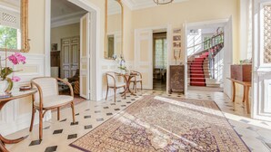 A spacious foyer with a patterned rug, a staircase with red steps, and a large mirror. - Château d'Avesnes Le Castelet (Avesnes-en-Bray)