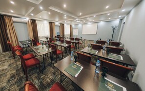 A hotel conference room with multiple tables, chairs, and a projector screen. - Ulan-Ude Park Hotel (Ulan-Ude)