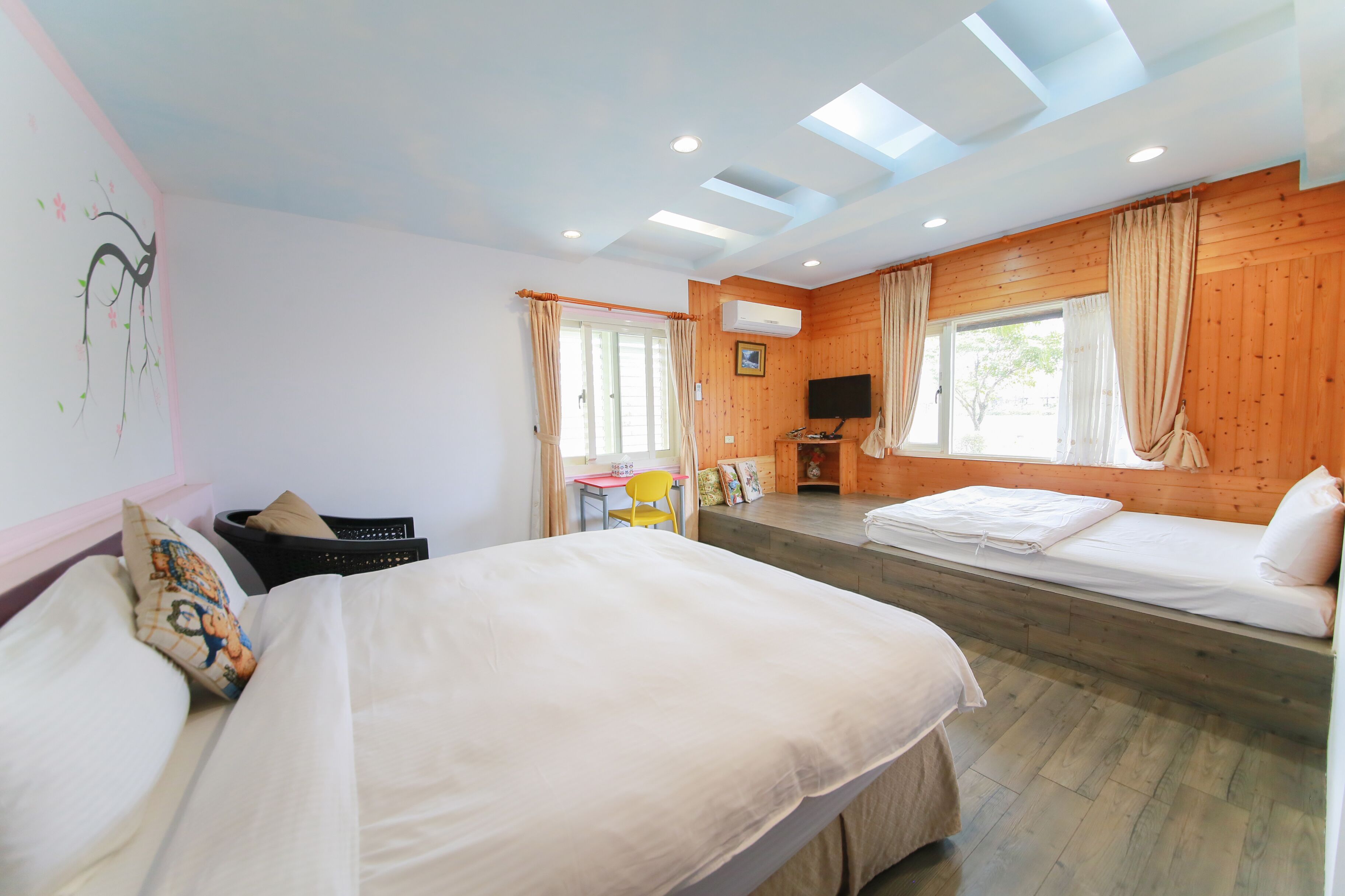 A room with two beds, a desk, a chair, and a TV.