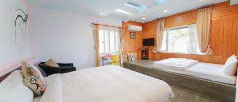A room with two beds, a desk, a chair, and a TV.