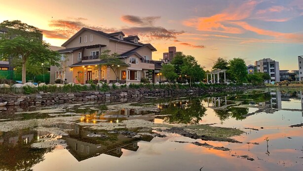 A residential area with houses, a pond with lily pads, and a sunset sky. - Dong Shan He B&B (Dongshan)
