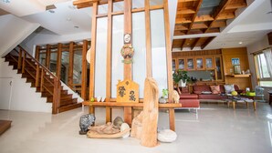 A spacious living area with a wooden staircase, a wooden beam structure, and a sofa set. - Dong Shan He B&B (Dongshan)